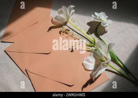Overhead view of white tulips and daffodils with envelopes on a table Stock Photo