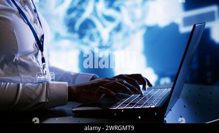 Admin writing artificial intelligence script code in cloud computing business establishment on laptop terminal. Tech savvy expert doing maintenance work in data center, upgrading AI systems Stock Photo