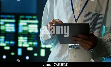 Certified technician strolling through server rows providing processing resources for different workloads. Adept expert monitoring supercomputers tasked with solving complex operations, close up Stock Photo