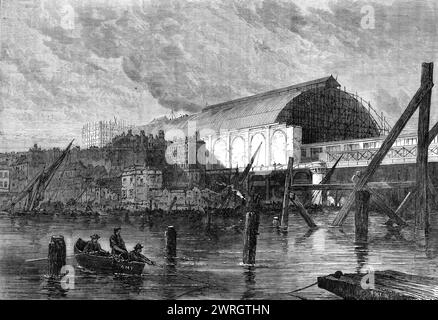 The Charing-Cross railway station, as seen from the river [Thames, London], 1864. 'This magnificent structure, with a semicircular roof of iron and glass, far exceeds in span the much-admired roofs of the Great Northern Railway at King's-cross, which are only 105 ft., while these are nearly 200 ft. The passenger platforms at present in use project beyond the limits of this glass roof upon a part of the bridge, which widens out from the ordinary breadth of four lines of rail into a fanlike form, containing seven lines...The contract was enormously heavy, considering the short distance of the li Stock Photo