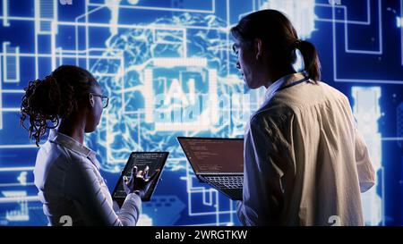 IT team members develop artificial intelligence neural networks architecture inspired by human brain, setting up AI machine learning algorithms using binary language programming on tablet and laptop Stock Photo