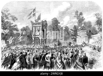 Visit of the Prince and Princess of Wales to Denmark: arrival at the Castle of Bernstorf, 1864. The future King Edward VII and Queen Alexandra in Scandinavia. 'A triumphal arch was erected immediately outside the entrance-gate, in the decorations of which oak-leaves and forest flowers and berries were combined with the produce of private gardens. The English and Danish flags floated from the summit, and the arms of the two countries, painted upon shields, were exhibited from each front...For more than a mile from the gates of the castle the road was lined with a well-dressed crowd...welcoming Stock Photo