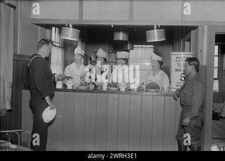 Mrs. E.L. Smith, Mrs. Jay Gould, Mrs. H.B. Duryea, Mrs. Lawr. Keene, 1918. Mrs. Edward L. Smith, Mrs. Jay Gould, Mrs. Herman B. Duryea (Ellen Homer Winchester), and Mrs. Lawrence Keene behind a counter, serving military personnel at the Y.M.C.A. Bryant Park Eagle Hut, New York City which was opened during World War I. Stock Photo