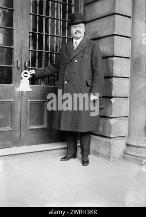 Mayor Hylan, between c1915 and c1920. New York City's Mayor John Francis Hylan (1868-1936) with advertisement for government bonds from Third Liberty Loan as a Liberty bell-shaped cut-out hanging from a doorknob. Stock Photo