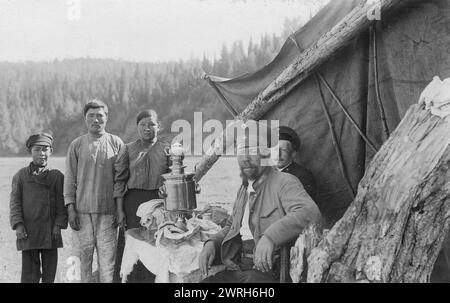 G.I. Ivanov and a Shoria Family at the Table with Samovar Near the Tent, 1913. From a collection of 109 photographs taken during a 1913 topographic expedition to the Gornaia Shoria in the Altai region and another topographic expedition to the Mrasskii region, Kuznetskii District (central part of the Gornaia Shoria). The photographs reflect both expedition activities and the life of the people in this region. Altai State Regional Studies Museum Stock Photo