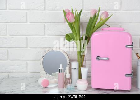 Cosmetic refrigerator and skin care products on white marble table Stock Photo