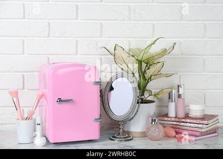 Cosmetic refrigerator and skin care products on white marble table Stock Photo