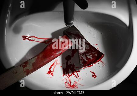 Axe with blood in sink, above view Stock Photo