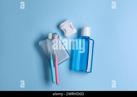 Fresh mouthwash in bottle, toothbrushes and dental floss on light blue background, flat lay Stock Photo