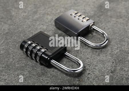 Locked steel combination padlocks on grey stone table, closeup Stock Photo