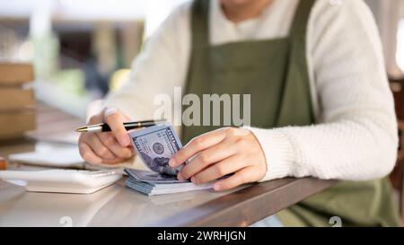 A cropped shot of a female small business owner managing her shop budget, calculating, and counting cash. people and financial concepts Stock Photo