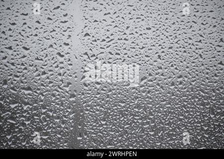 Raindrops on a window, precipitating from a drizzle outside, create a serene ambiance associated with the rainy season Stock Photo