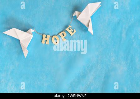 Message of hope concept. White dove origami carrying word letters in sky blue background. Stock Photo