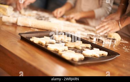 Bake, gingerbread man biscuits and people in kitchen of home, closeup for cooking or pastry preparation. Food, baking or cookies with hands of family Stock Photo