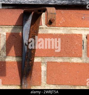 Old rusty wall bracket on a red brick textured wall. Stock Photo