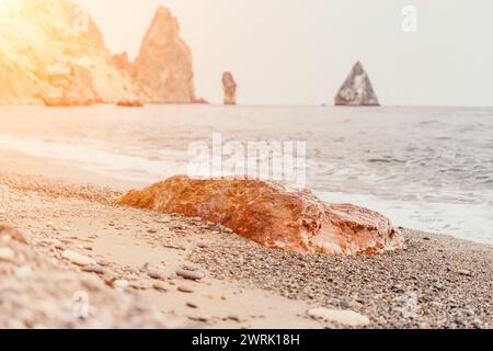 Large red jasper rock on the beach, with the sea in the background. Big Red Jasper Stone Close Up Stock Photo
