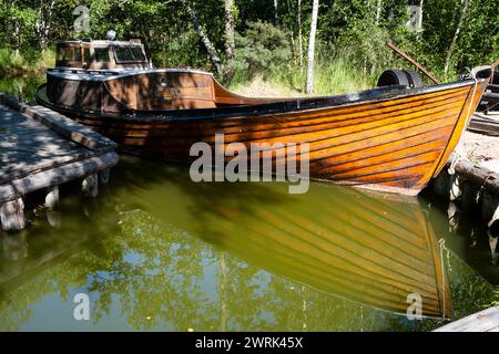 TRADITIONAL CLINKER BUILT BOAT: A traditional clinker built wooden boat at Brobacka Gästhem Cafe Garden and Boat Canal on Åland in the Baltic Sea in Finland. The Åland Islands are situated in the Baltic Sea off the southwest coast of Finland. Åland is an autonomous, demilitarised, Swedish-speaking region of Finland. The Åland archipelago consists of more than 6,700 islands, but the population of over 30,000 live on only 60 islands. Stock Photo