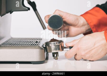 Pressing ground coffee in handle for extracting in espresso machine Stock Photo