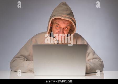 Older criminal man using computer for remote money robbery Stock Photo