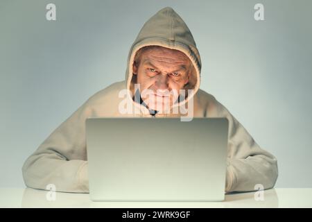 Older criminal man using computer for remote money robbery Stock Photo