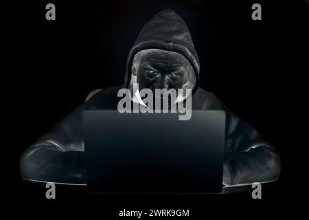 Older criminal man using computer for remote money robbery Stock Photo