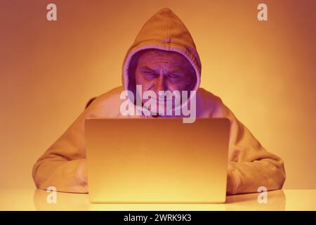 Older criminal man using computer for remote money robbery Stock Photo