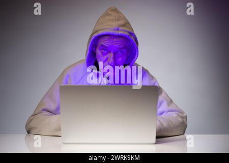 Older criminal man using computer for remote money robbery Stock Photo
