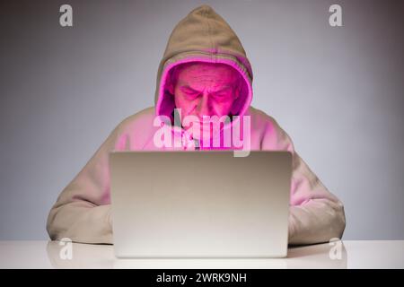 Older criminal man using computer for remote money robbery Stock Photo