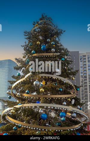 Decorated Christmas tree with shiny gold ornaments outside on the urban street Stock Photo