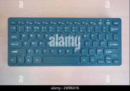 Wireless mini keyboard on a background of a wooden surface close-up. Stock Photo