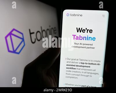 Person holding cellphone with webpage of Israeli AI coding company Tabnine Ltd. in front of business logo. Focus on center of phone display. Stock Photo