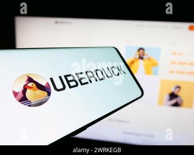 Smartphone with logo of American artificial intelligence music company Uberduck Inc. in front of website. Focus on left of phone display. Stock Photo