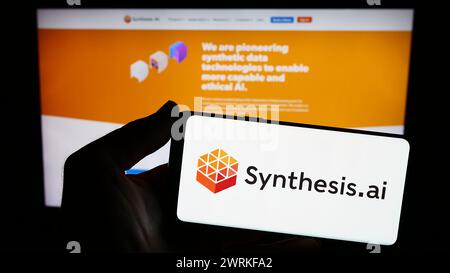 Person holding smartphone with logo of US artificial intelligence company Synthesis AI Inc. in front of website. Focus on phone display. Stock Photo