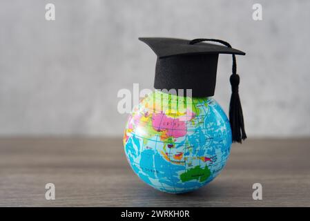 Graduation cap on top of world globe with copy space. Study abroad. foreign students concept. Stock Photo