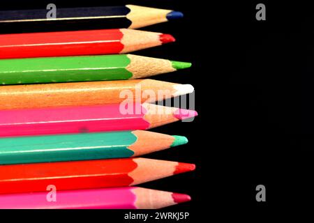 The picture shows colored pencils ready for work, which lie on a dark background. Stock Photo