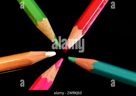 The picture shows colored pencils ready for use, which lie on a dark background with leads in the center. Stock Photo