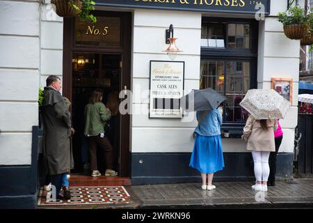People watch the coronation of King Charles III on screen at a pub in central London. Stock Photo