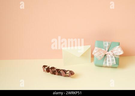 Green gift box, envelope, eucalyptus leaf on ivory table. pink wall background Stock Photo