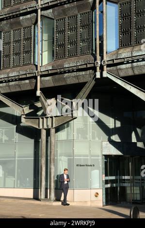 Male city worker using a mobile phone / smartphone outside offices of investment management firm T. Rowe Price, 60 Queen Victoria Street, London, UK Stock Photo