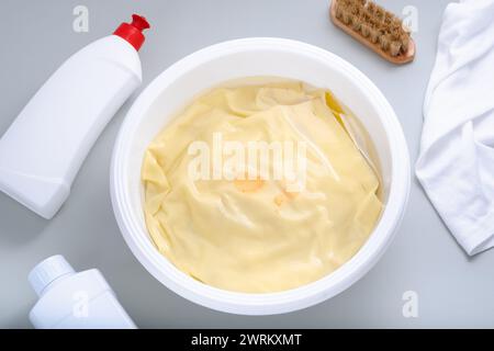 Close up dirty stain blood or tomato sauce on a yellow shirt pre-soaked for removal. Natural cleaning products and laundry manually. daily life stain Stock Photo