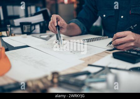 Architect using divider compass working on blueprint and make a note on book. Construction concept. Engineering tools Stock Photo