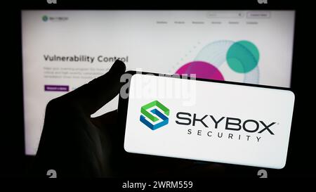 Person holding smartphone with logo of US cybersecurity company Skybox Security Inc. in front of website. Focus on phone display. Stock Photo