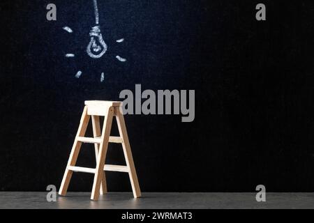 Wooden ladder with glowing light bulb drawn with chalk on blackboard, concept of new ideas, innovations and solutions in business Stock Photo