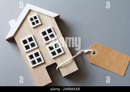 Miniature model of wooden house with tag, concept of selling, buying or renting real estate Stock Photo