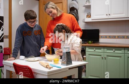 A joyful family moment as a mother and her children bond while baking together in their warmly lit kitchen, reflecting a loving family gathering. Stock Photo