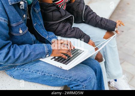 A close up view captures the anonymous hands of two young women, likely sisters, working together on a laptop, a symbol of collaborative technology us Stock Photo