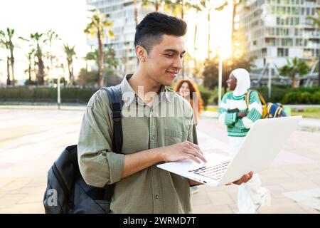 Diverse group of students with laptop enjoying outdoor campus life. Stock Photo