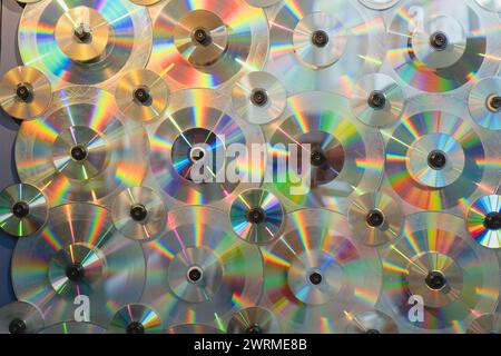 A vibrant display of light patterns refracted through a wall of arranged compact discs. Stock Photo