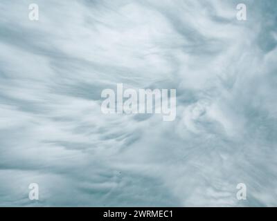Soft, wispy light blue clouds evoke a gentle, calming springtime atmosphere in this abstract texture. Stock Photo