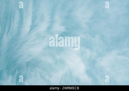 Soft, wispy light blue clouds evoke a gentle, calming springtime atmosphere in this abstract texture. Stock Photo